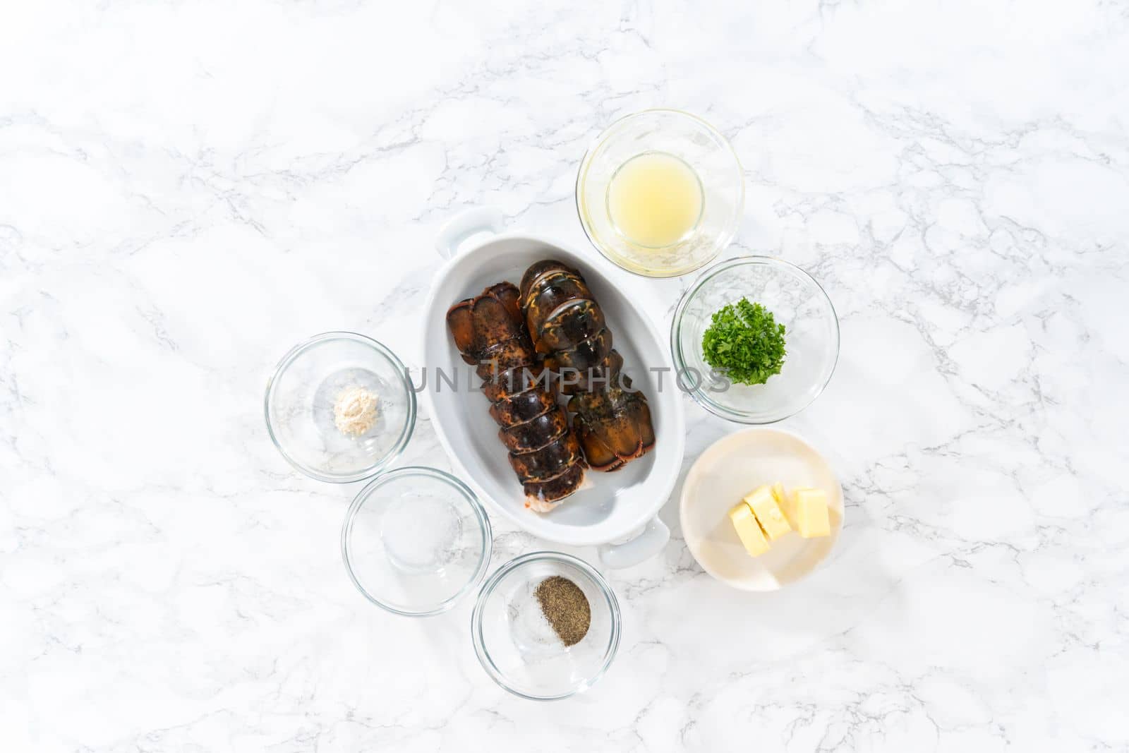 Flat lay. Measured ingredients in glass mixing bowls to prepare garlic lobster tails.
