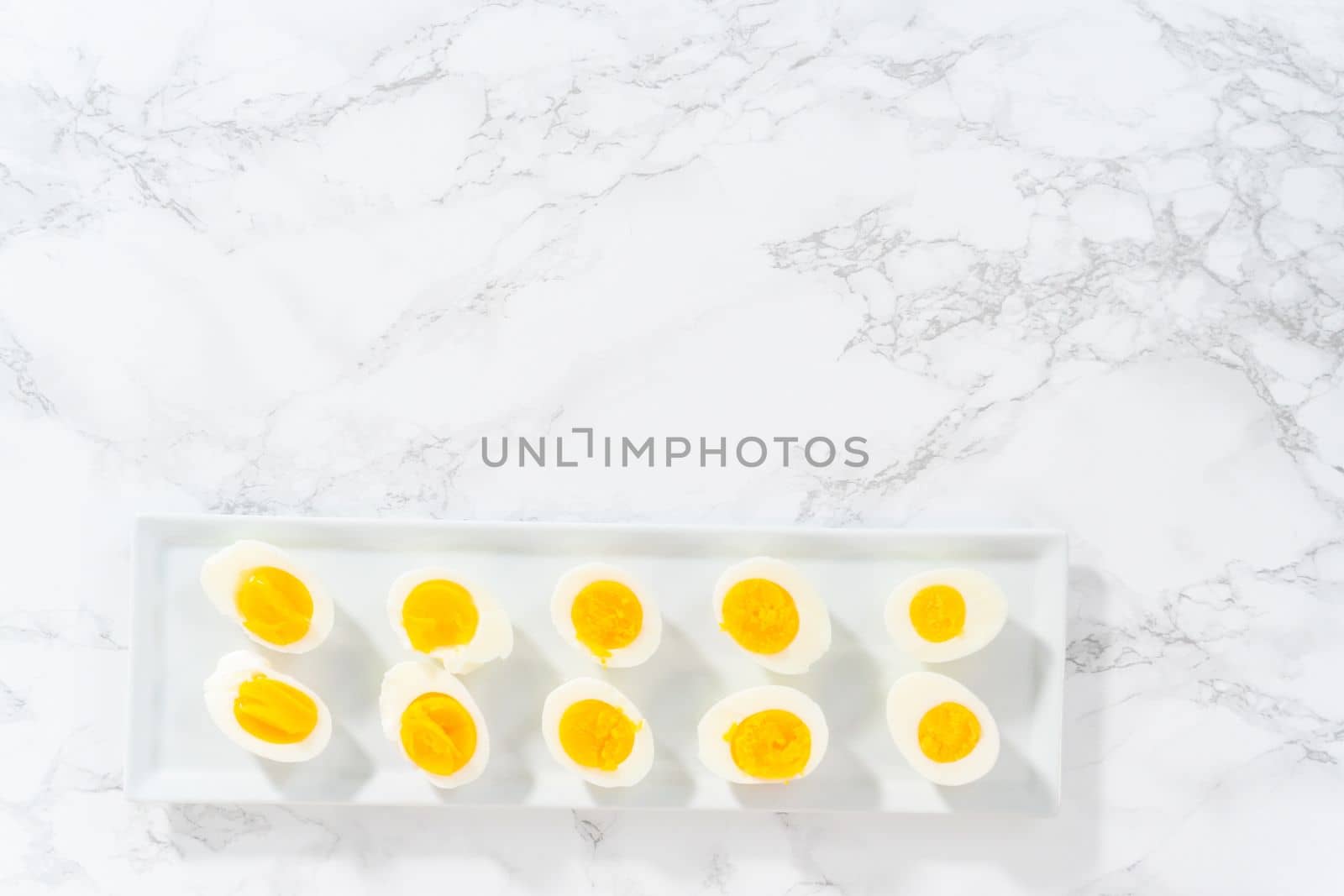 Sliced hard-boiled eggs on a white serving plate.
