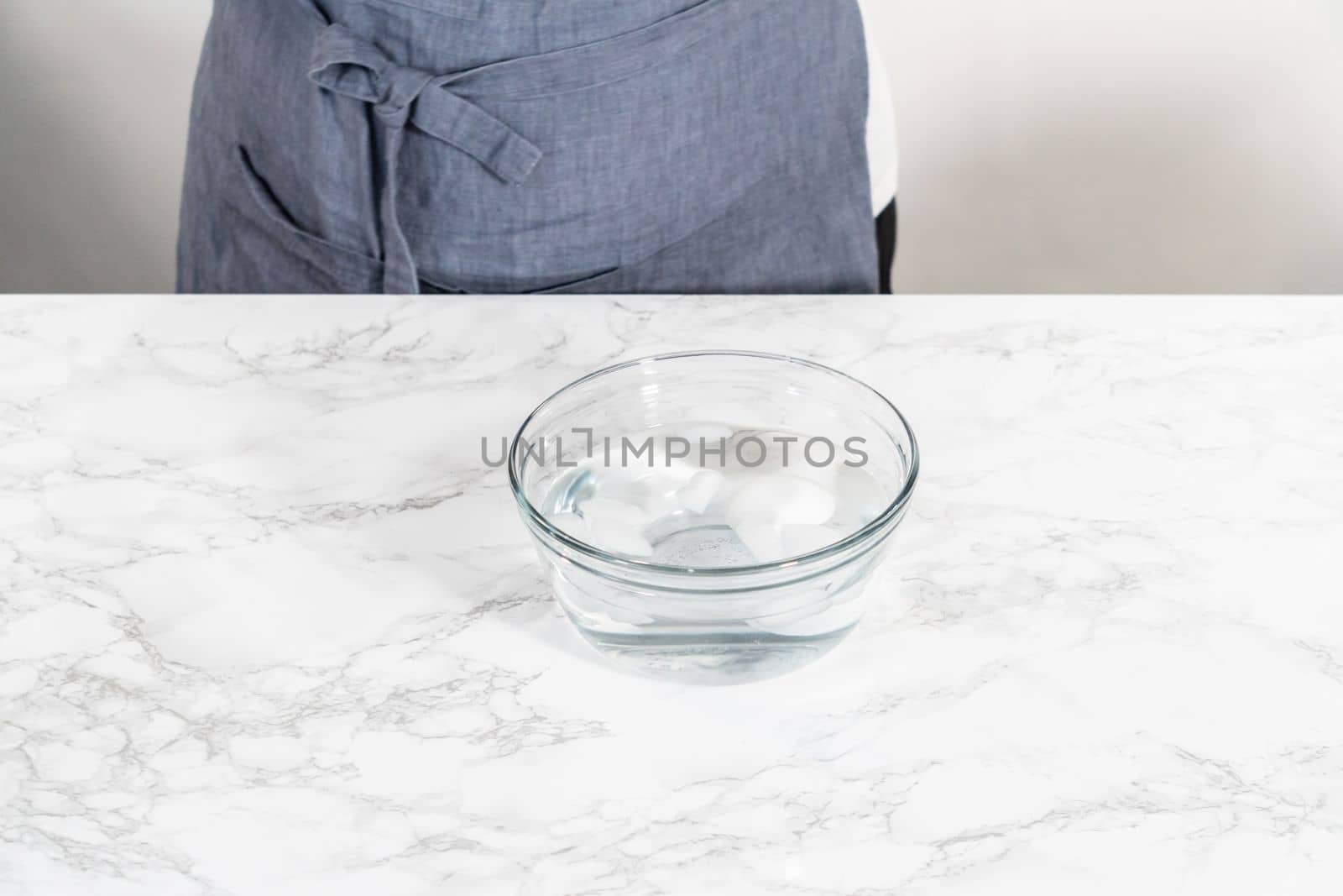 Cooling hard-boiled eggs in a glass bowl with cold water and ice cubes.