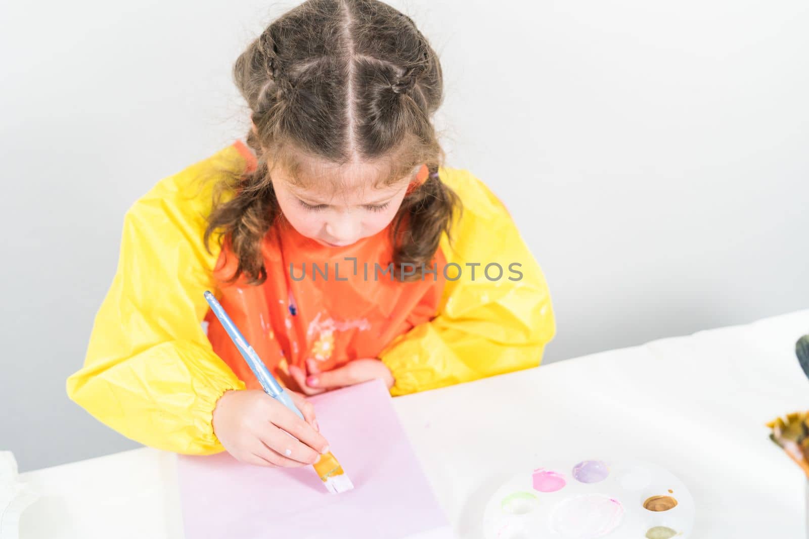 Little girl working on an art project with acrylic paint at homeschool.