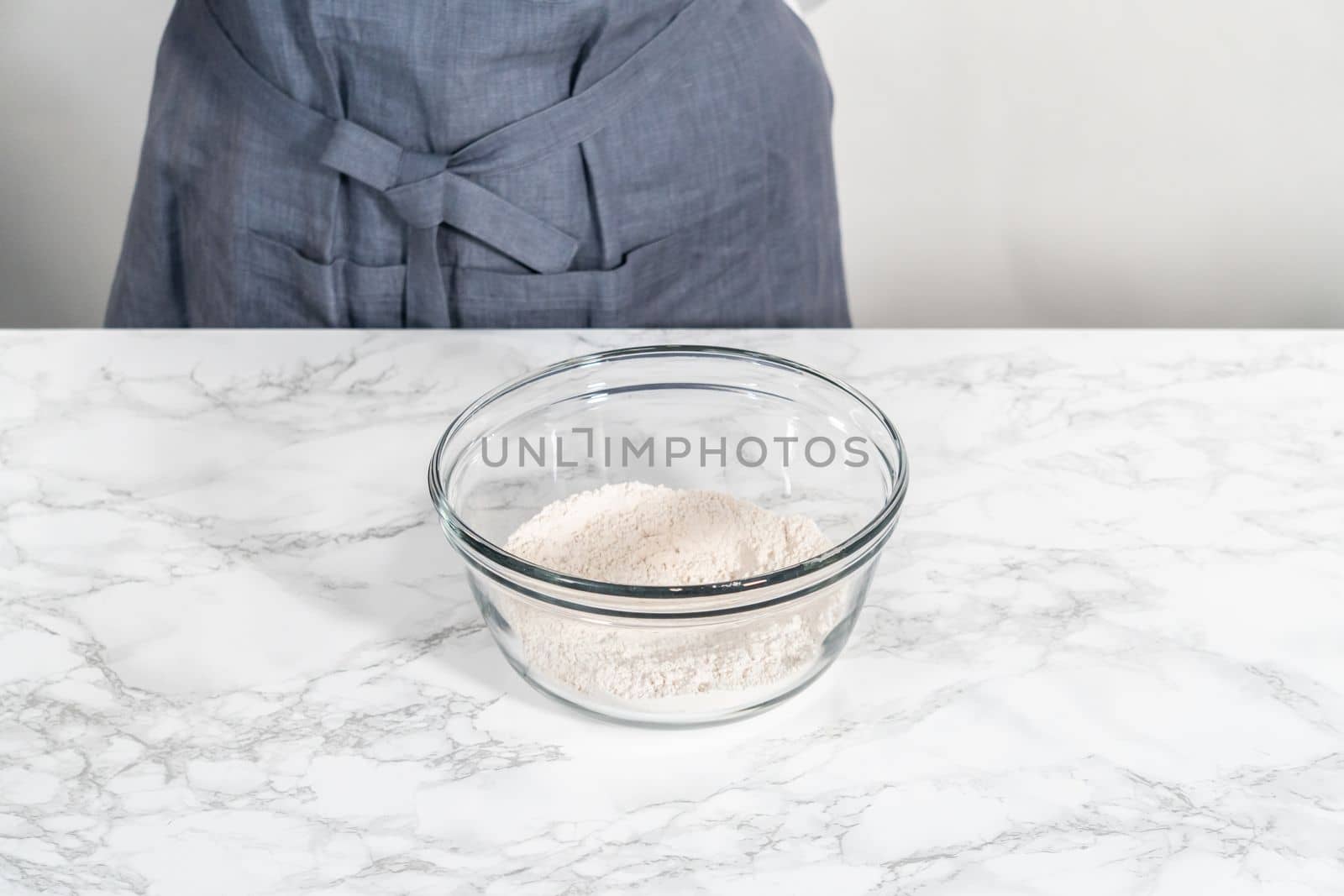 Mixing dry ingredients in a large glass mixing bowl to bake soft oatmeal raisin walnut cookies.