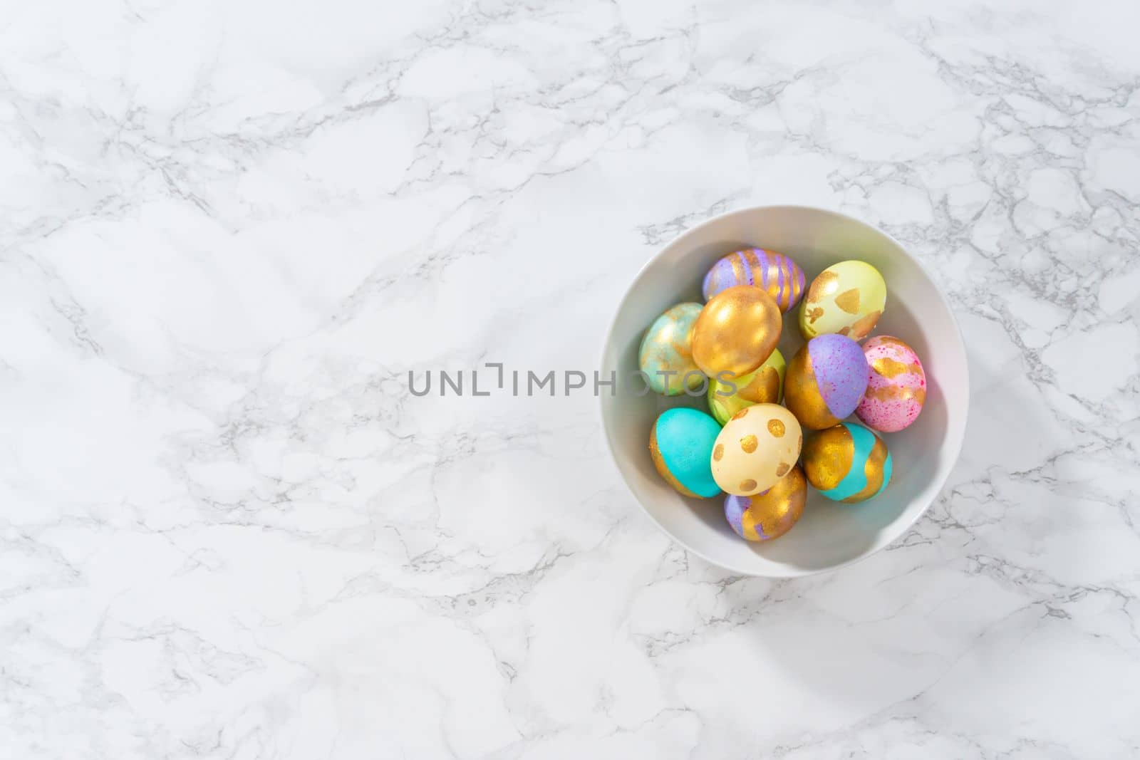 Colored and painted with gold hard-boiled eggs on a marble background.