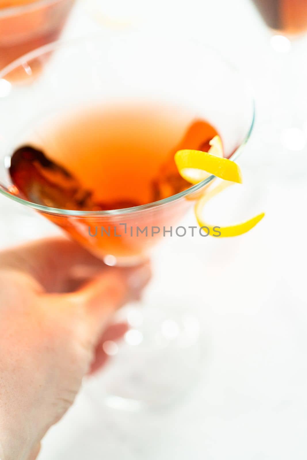 Cosmopolitan cocktail in a martini glass and decorated with a lemon swirl.