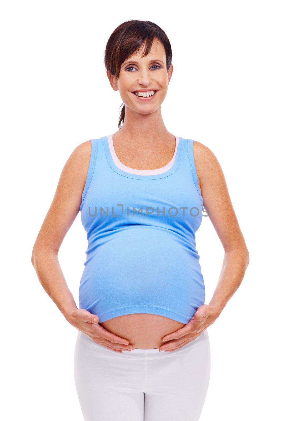 Glowing with the promise of new life. A young pregnant woman holding her tummy and smiling at the camera