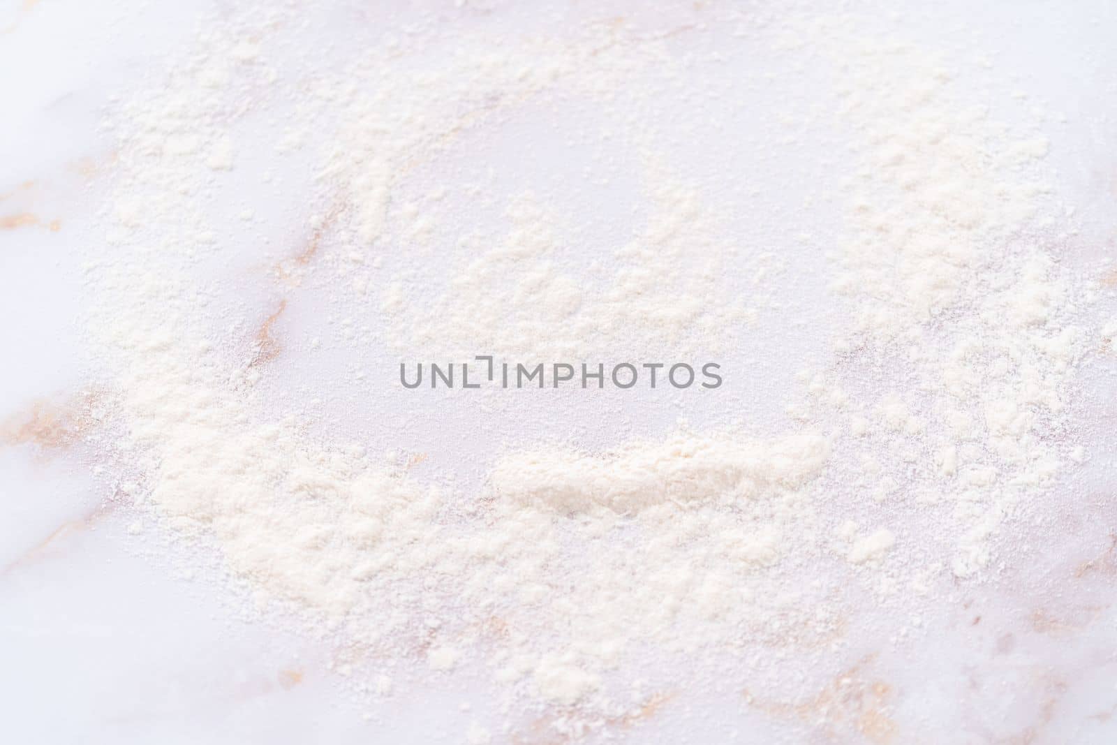 White flour sprinkled over the pink marble surface during the baking.