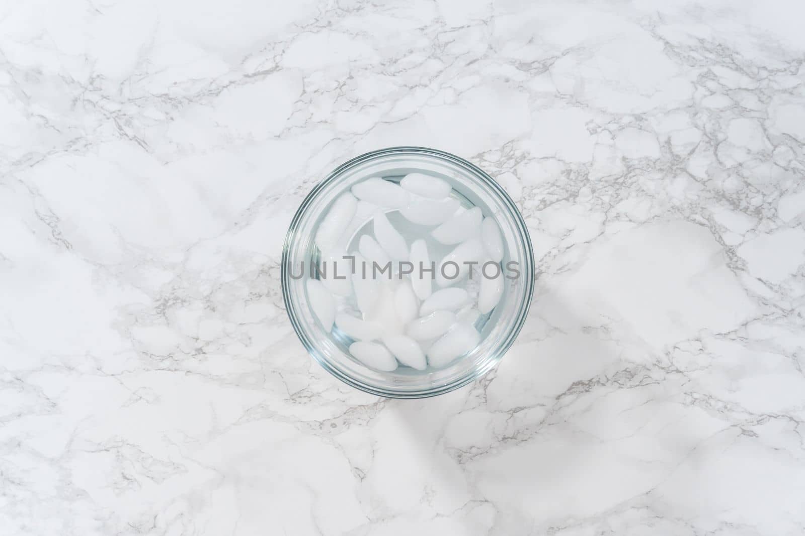 Cooling hard-boiled eggs in a glass bowl with cold water and ice cubes.