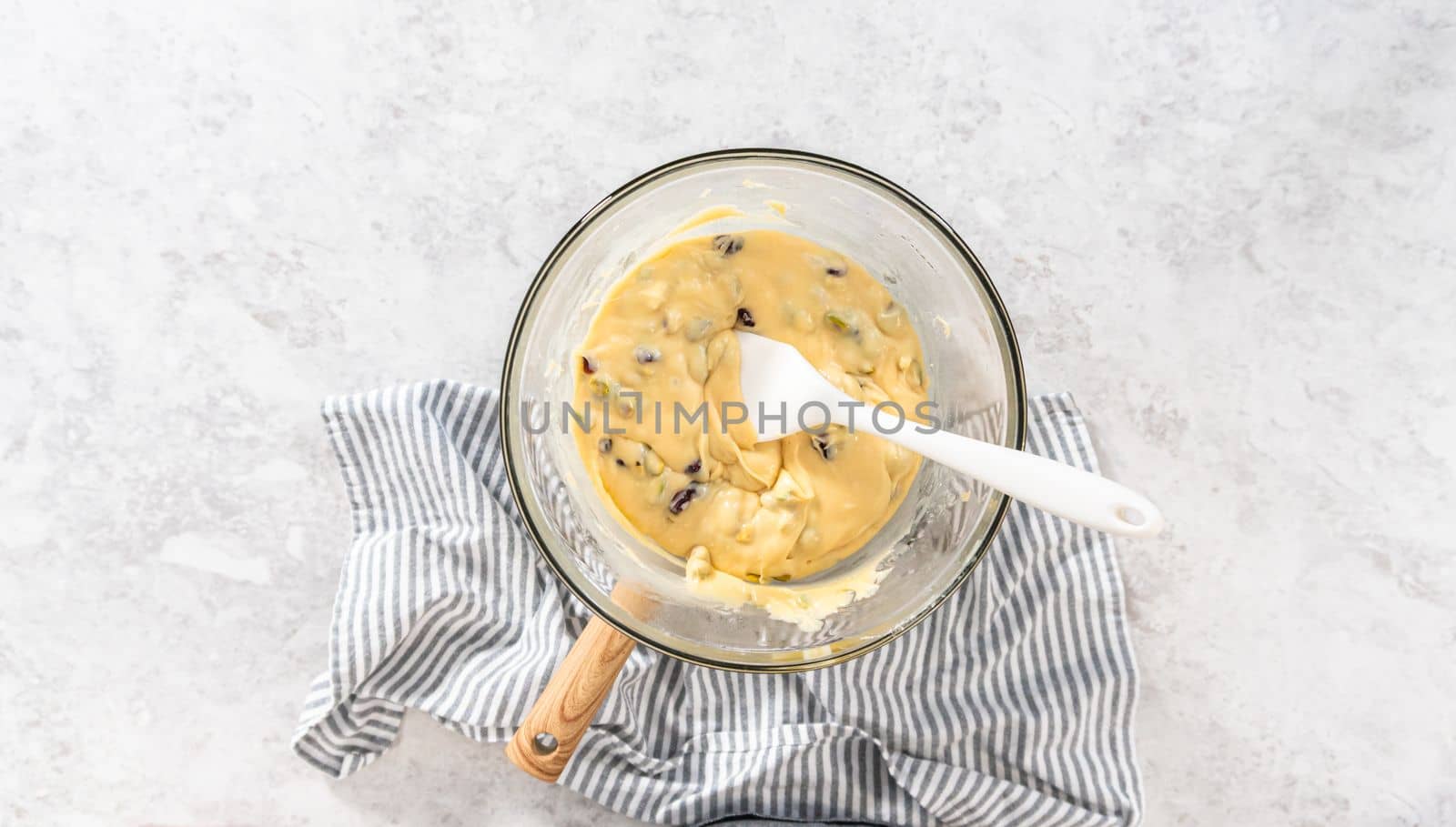 Flat lay. Melting white chocolate chips and other ingredients in a glass mixing bowl over boiling water to prepare cranberry pistachio fudge.