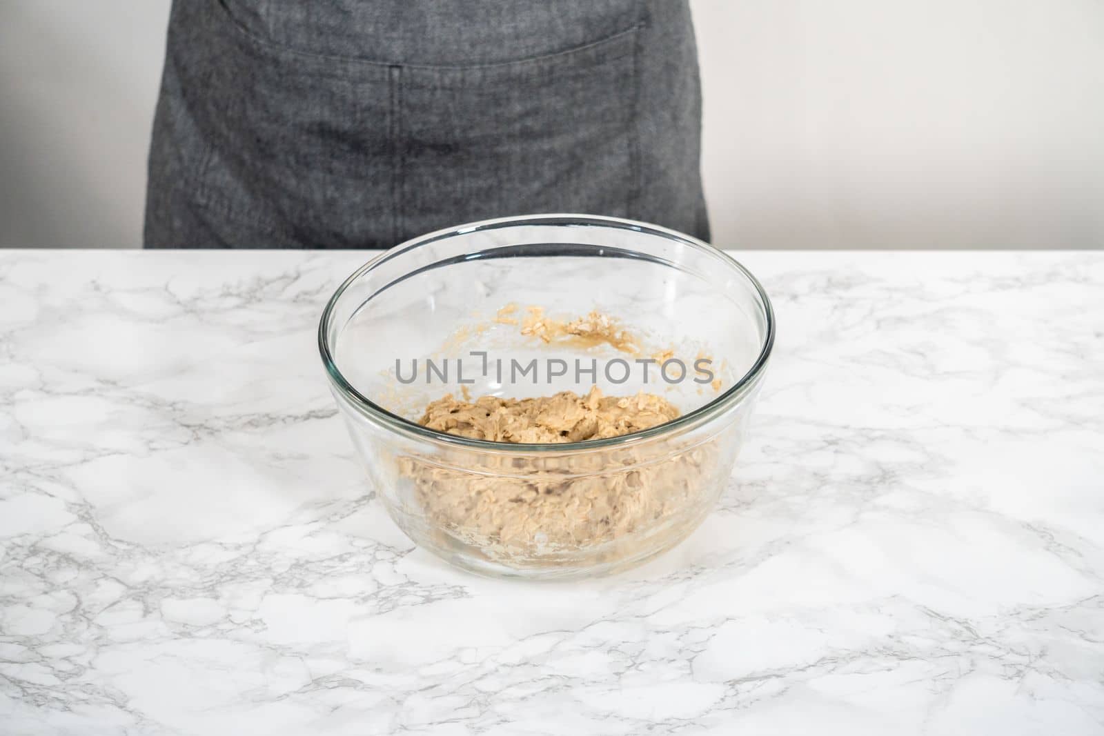 Mixing ingredients in a large glass mixing bowl to bake banana oatmeal muffins.