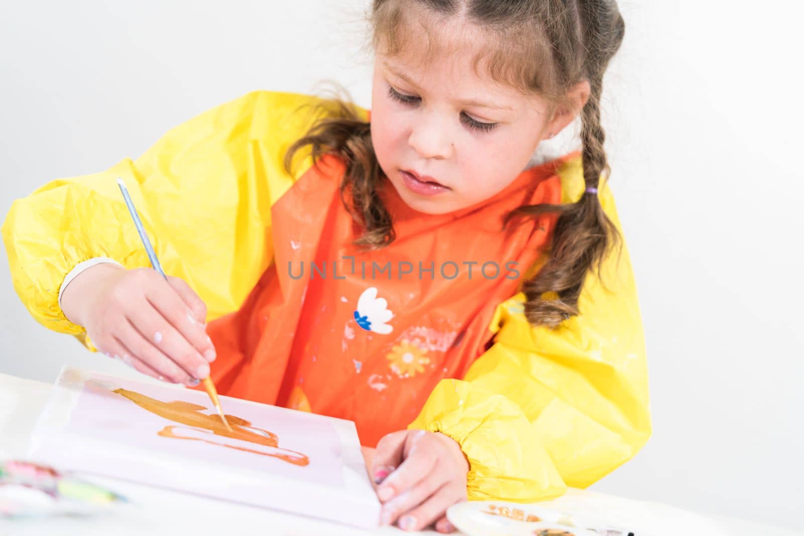 Little girl working on an art project with acrylic paint at homeschool.