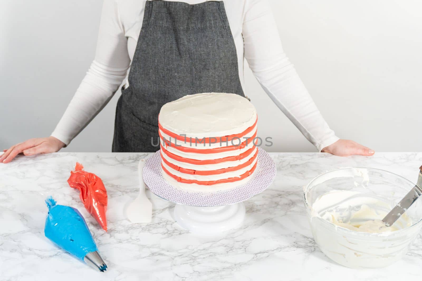 Decorating chocolate cake with white, red, and blue buttercream frosting for July 4th celebration.