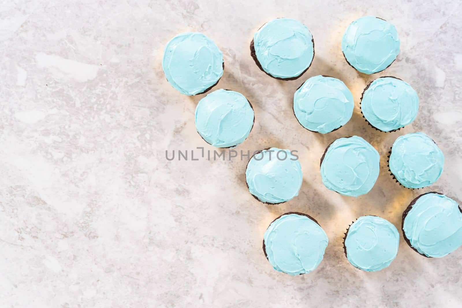 Flat lay. Decorating chocolate cupcakes with buttercream frosting and rainbow candy.