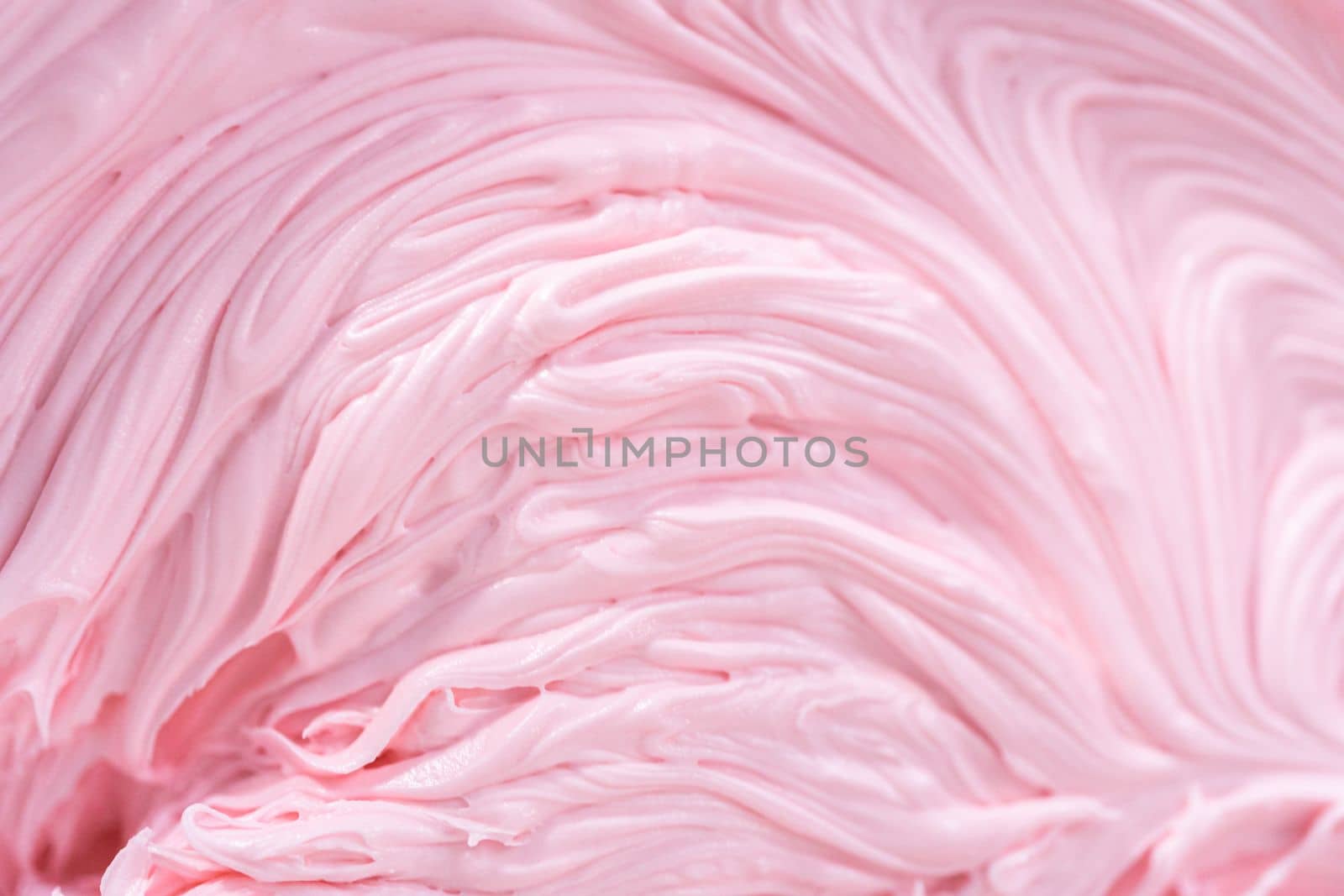 Close up view. Mixing in pink food coloring into a vanilla buttercream frosting for decorating funfettti bundt cake.