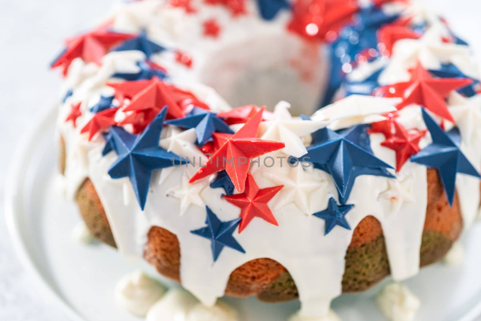 July 4th bundt cake covered with a vanilla glaze and decorated with chocolate stars on a white plate.