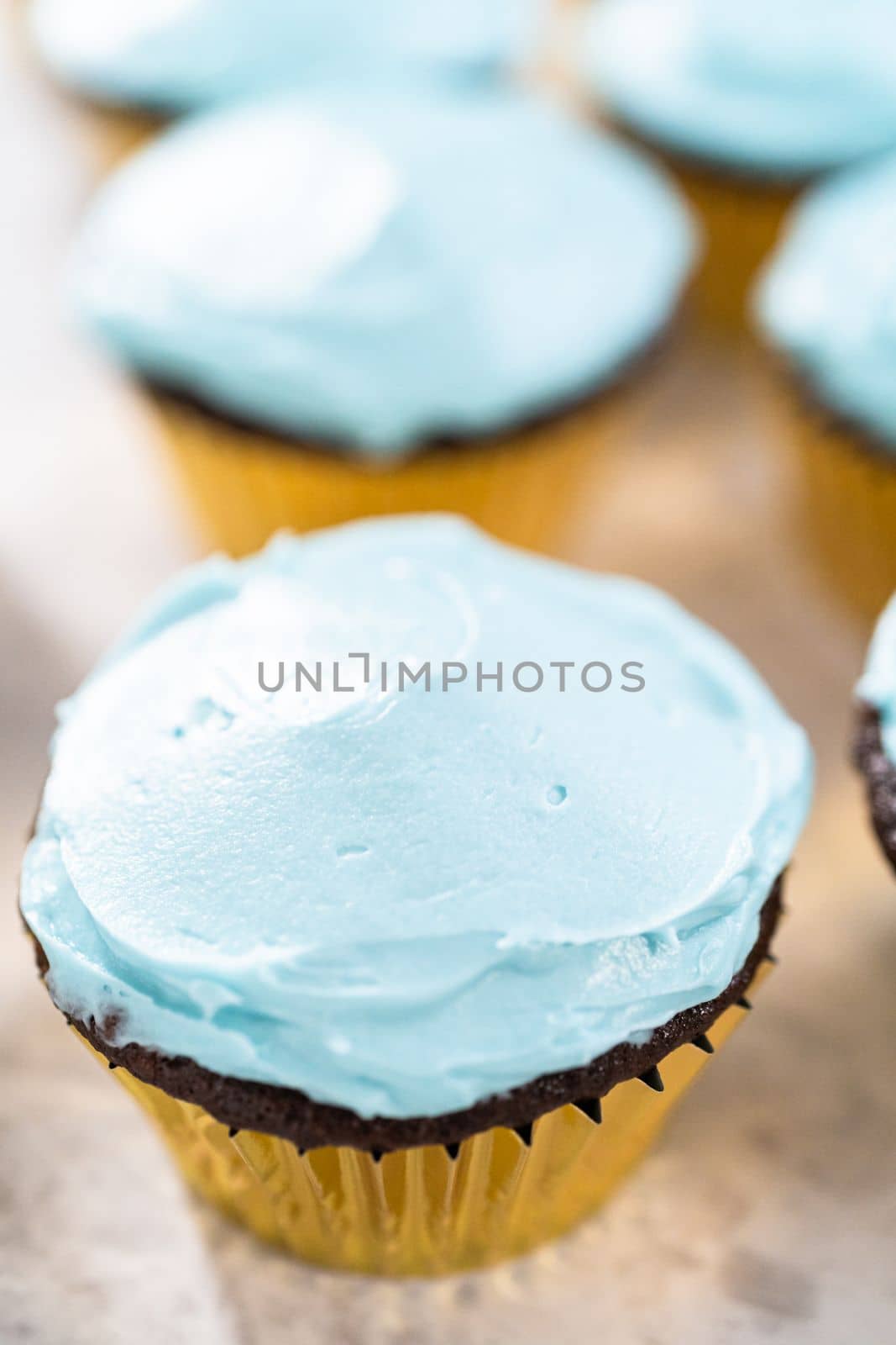 Decorating chocolate cupcakes with buttercream frosting and rainbow candy.