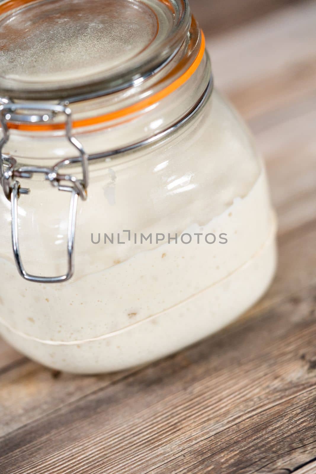 Feeding sourdough starter in a glass mason jar for baking artisan bread.