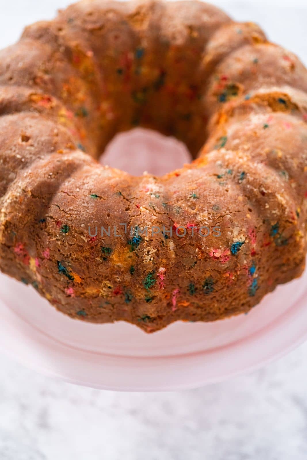 Close up view. Funfettti bundt cake prepared for frosting on a cake stand.