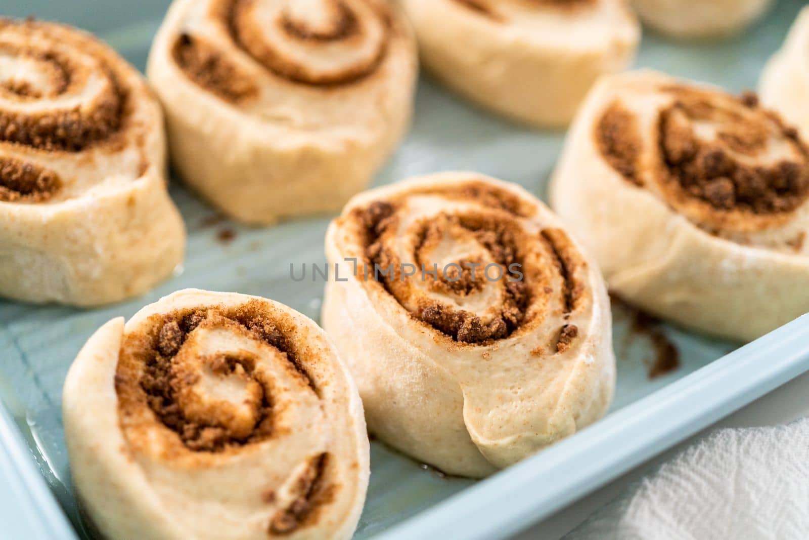 Unbaked cinnamon rolls in a blue baking pan.