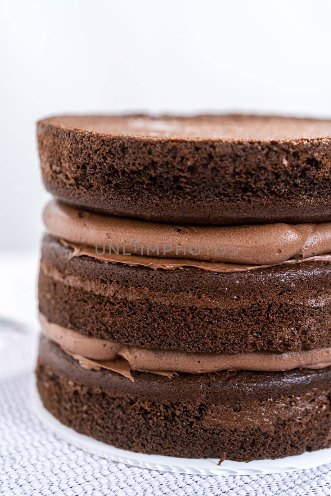 Covering chocolate cake with a crumb layer of chocolate buttercream frosting.