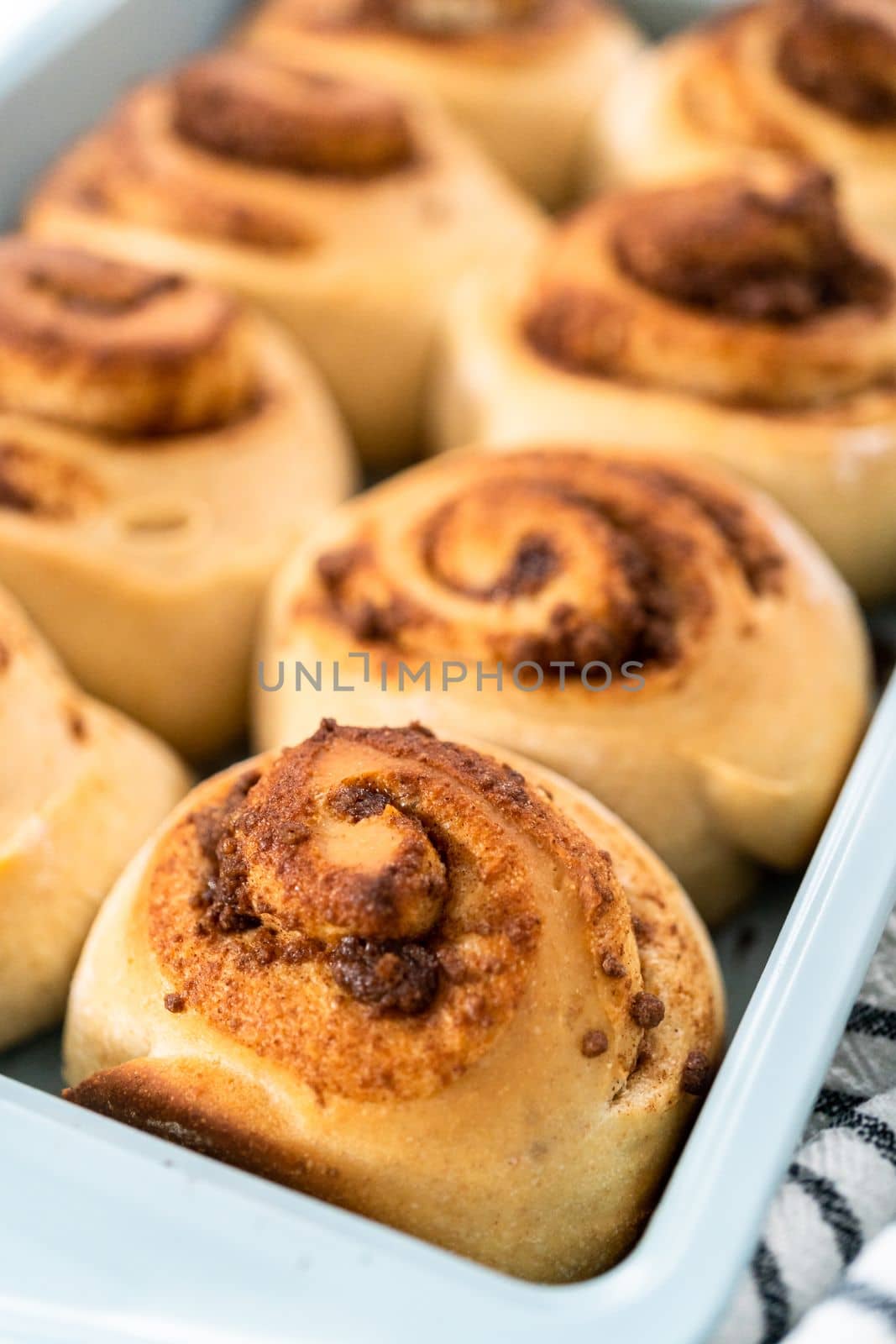 Freshly baked cinnamon rolls in a blue baking pan.