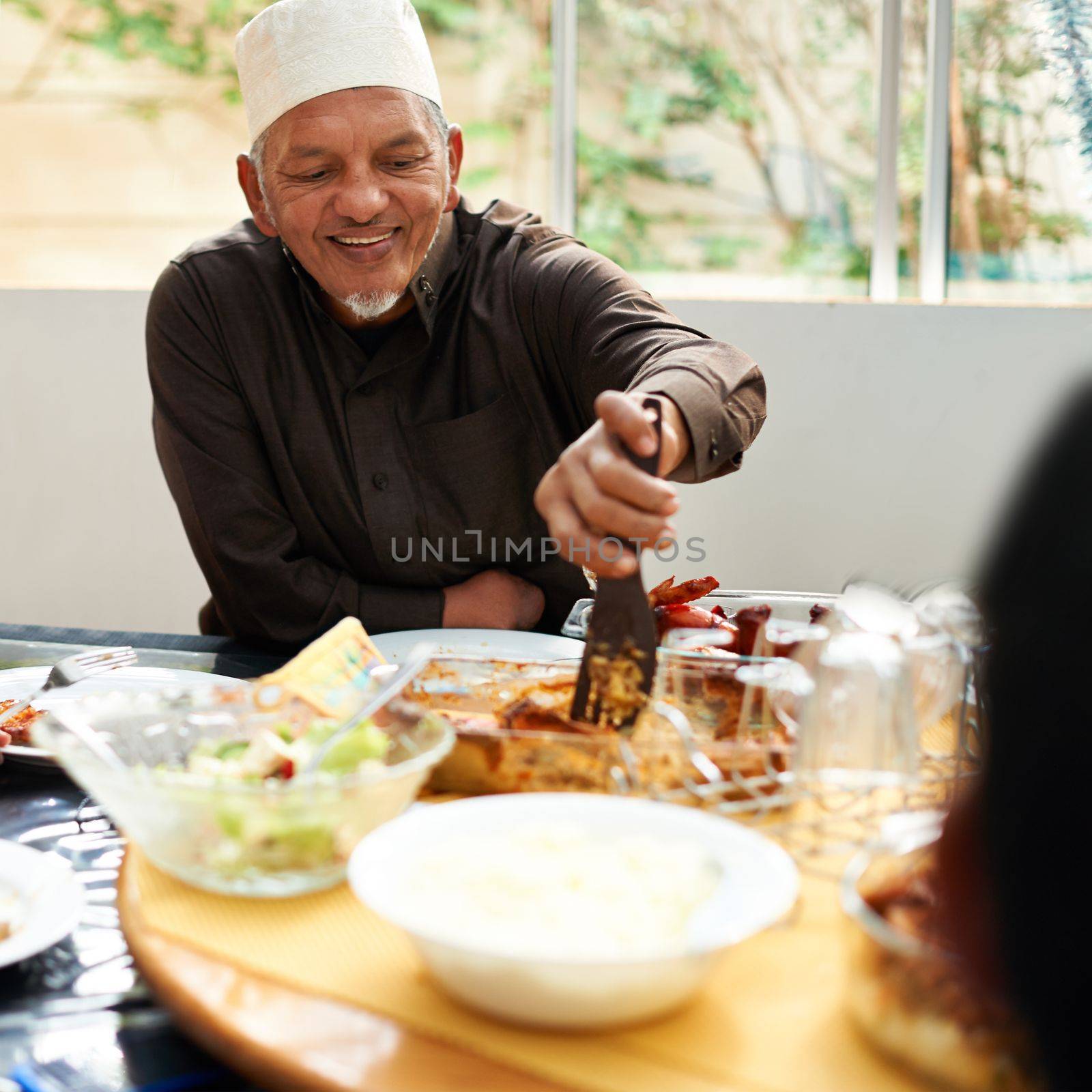 Family feast. a happy muslim man enjoying a meal with his family. by YuriArcurs