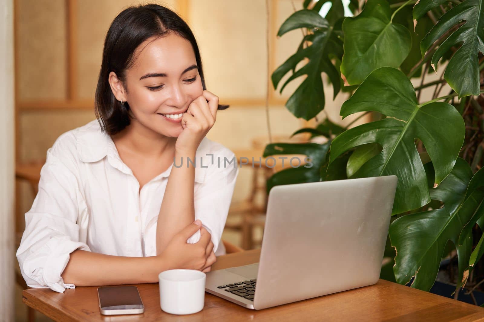 Beautiful brunette girl with laptop, sitting in cafe, working remotely, freelancing while sitting in coworking space.