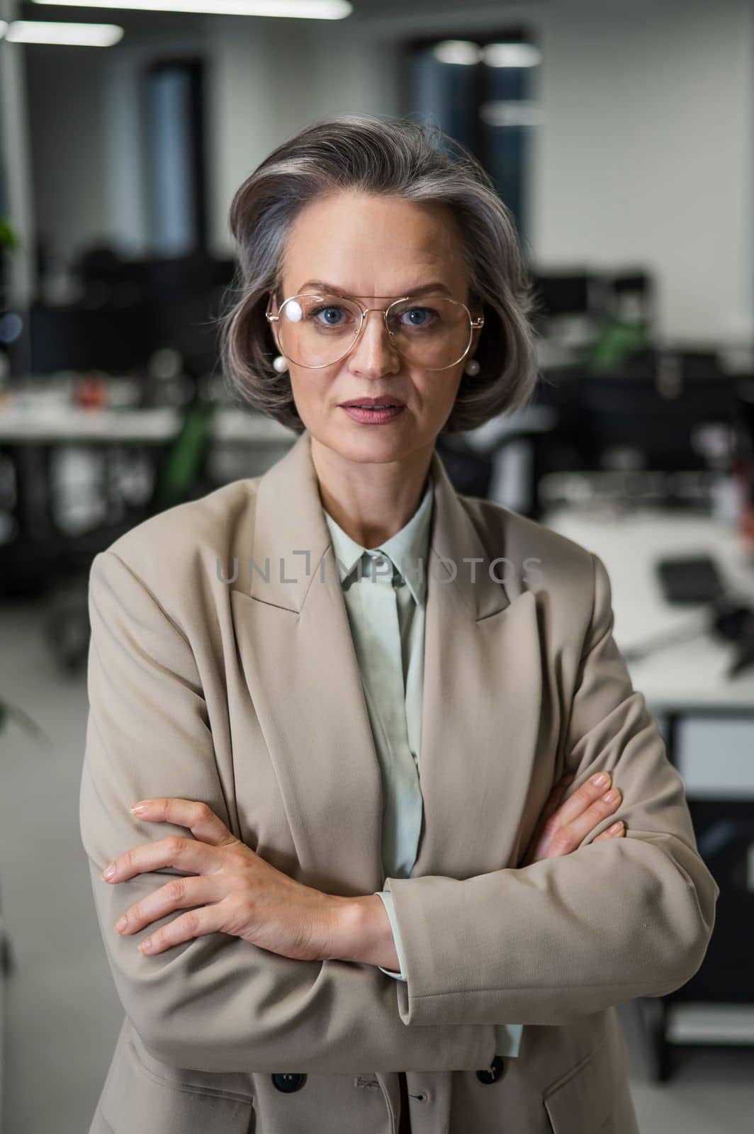 Portrait of an attractive mature caucasian woman with arms crossed on her chest in the office. by mrwed54