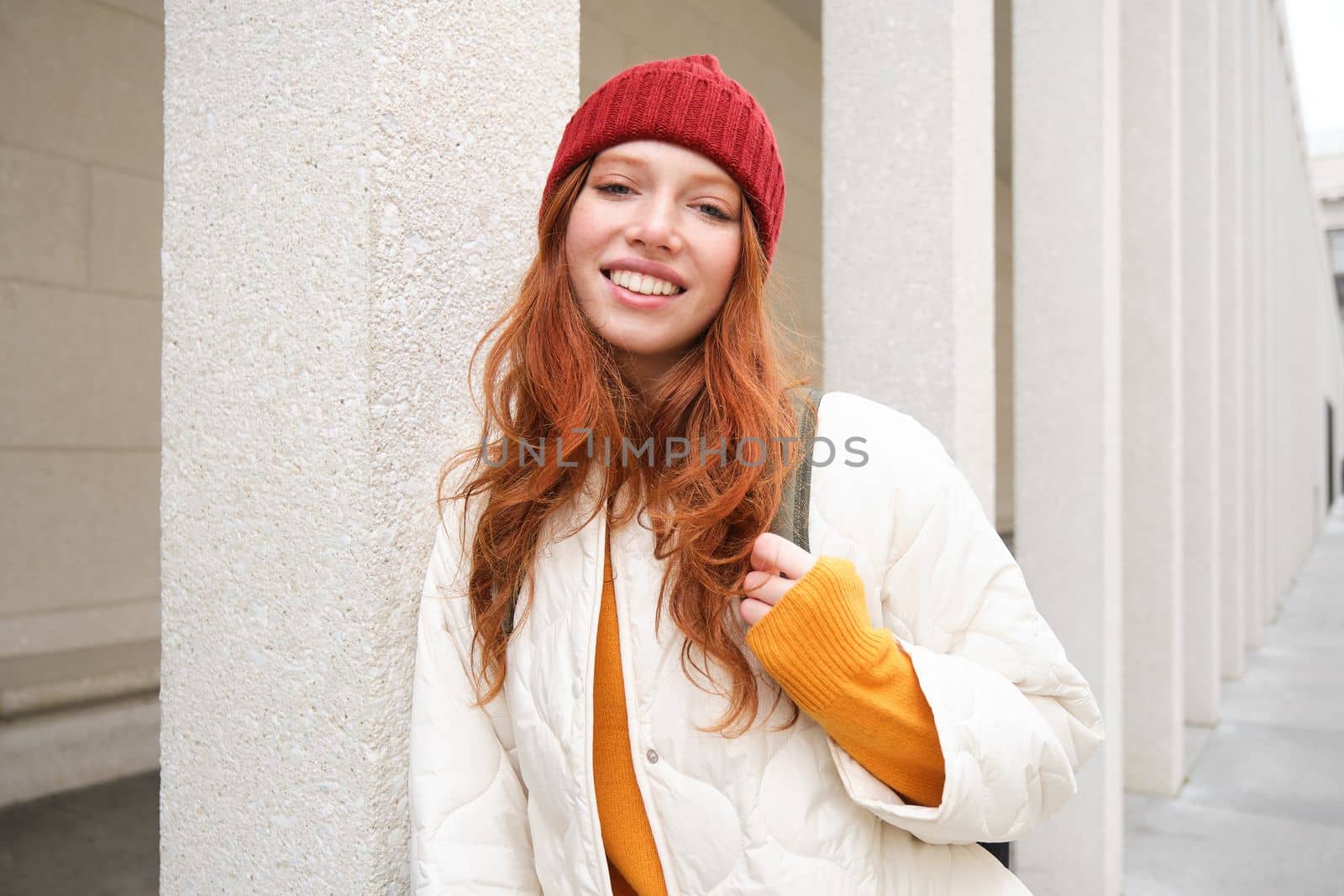 Female tourist in red hat with backpack, sightseeing, explores historical landmarks on her trip around europe, smiling and posing on street by Benzoix