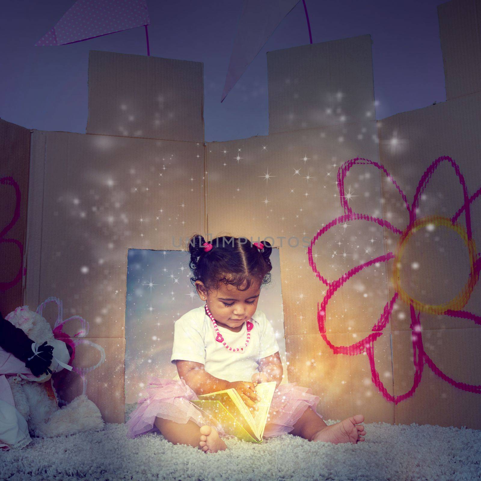 Her very first fairytale. an adorable little girl sitting on the floor and reading a glowing book