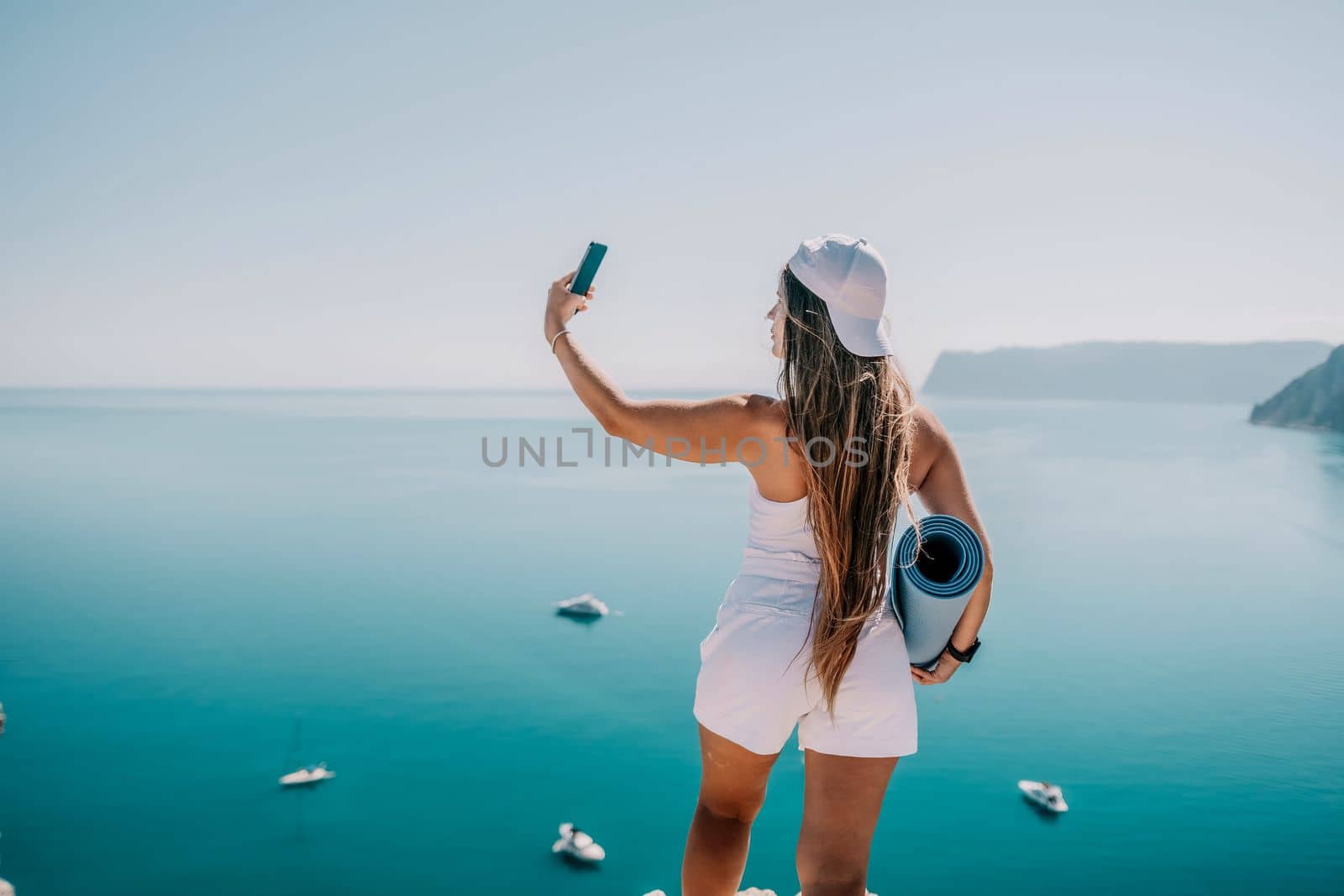 Young woman with black hair, fitness instructor in pink sports leggings and tops, doing pilates on yoga mat with magic pilates ring by the sea on the beach. Female fitness daily yoga concept