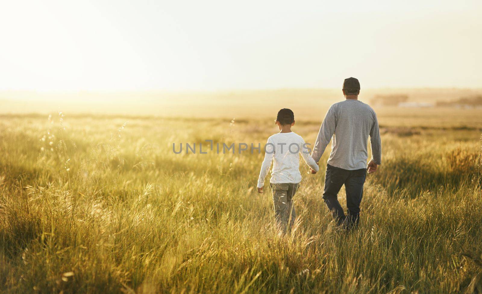 Theres beauty in simplicity. a man taking his son for a walk out on an open field