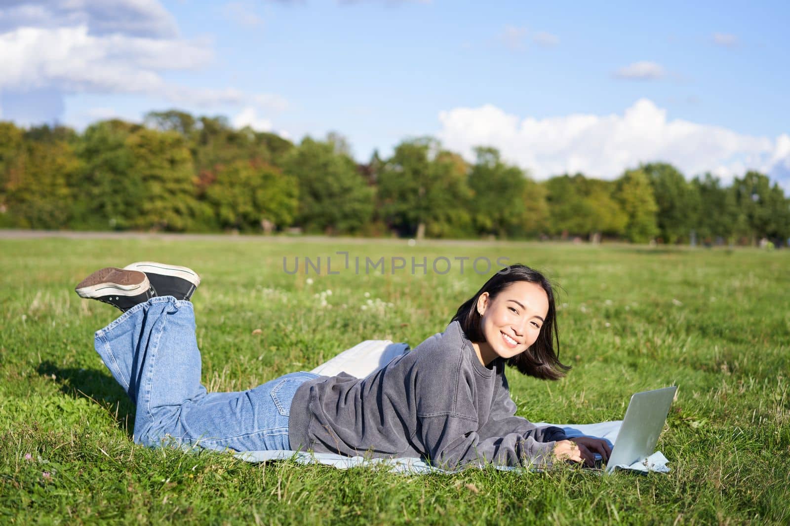 Leisure and people. Happy young woman lying in park on blanket, using laptop, relaxing outdoors and watching videos online on computer by Benzoix