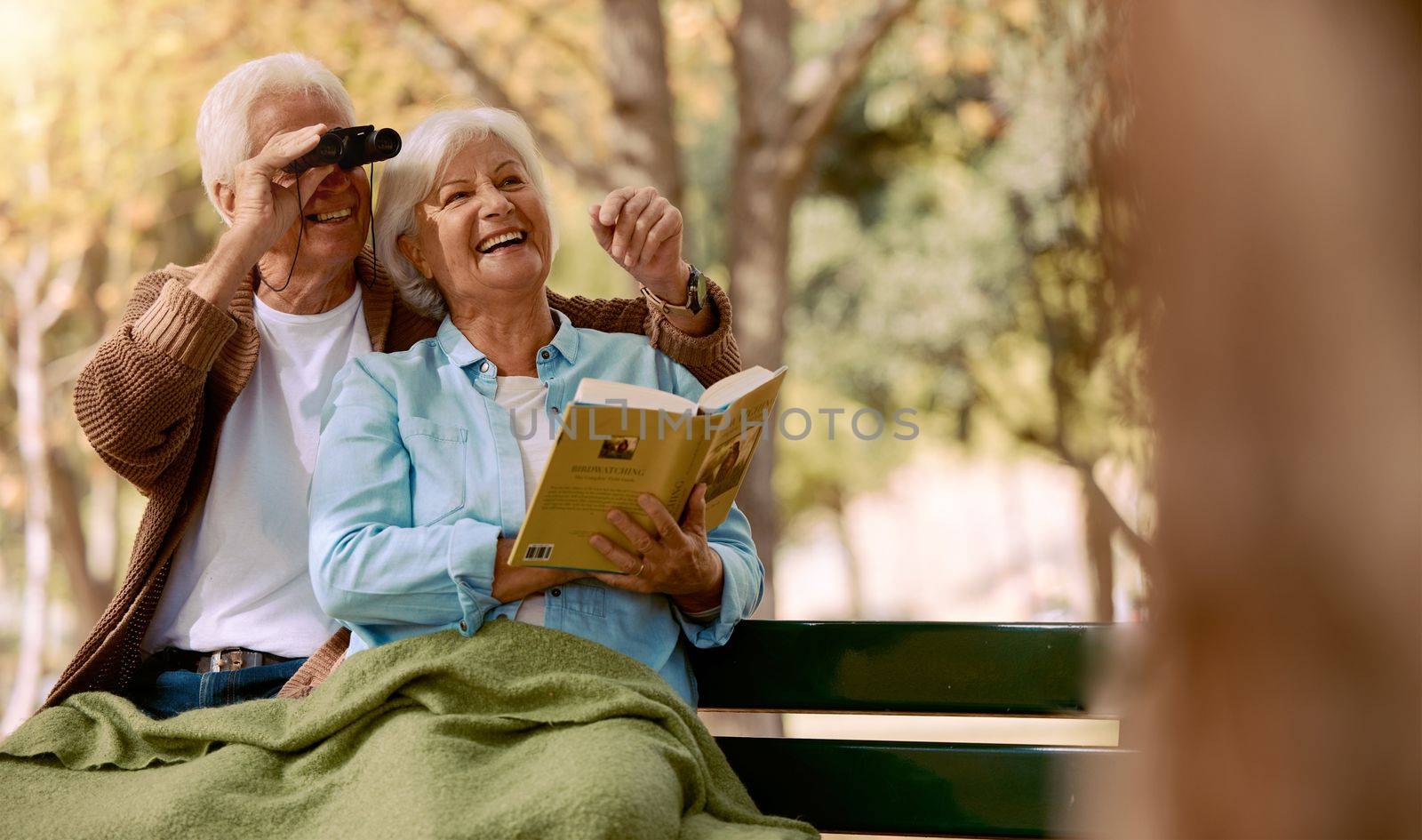 Love, senior couple and watching birds with book, binocular and romantic together. Romance, mature man and elderly woman in nature, happy and talking about animals, notebook and park bench for hobby