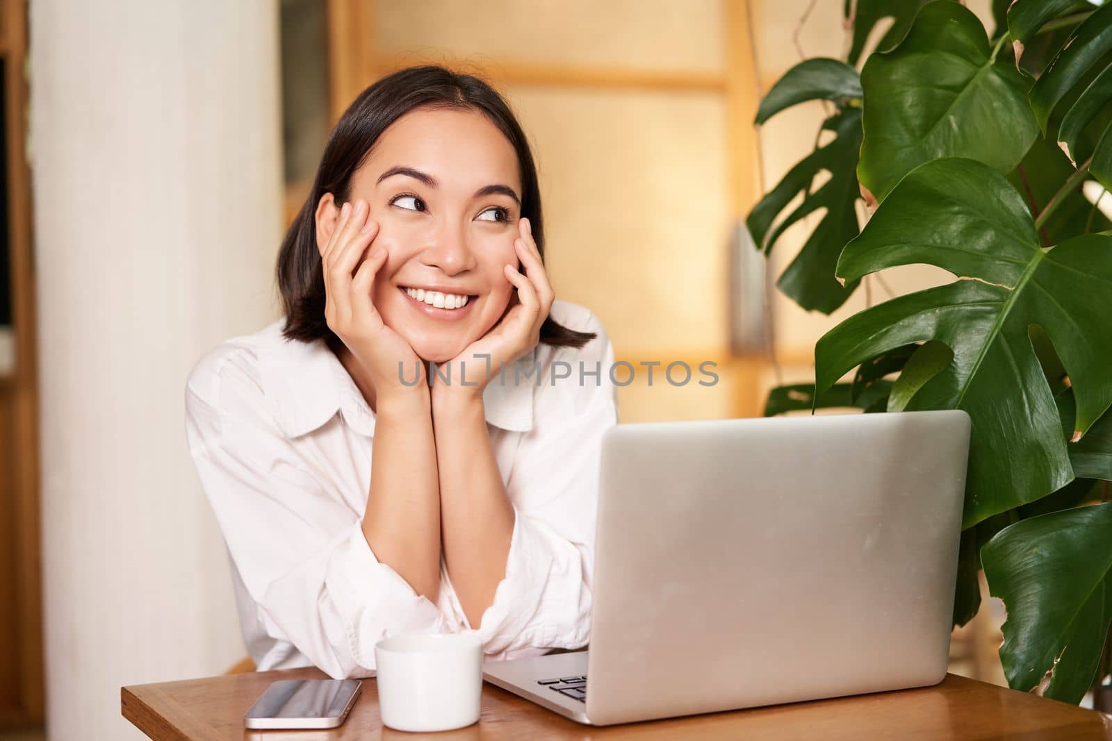 Confident young stylish woman with laptop, sitting in cafe and working, freelancer in co-working space with cup of coffee.