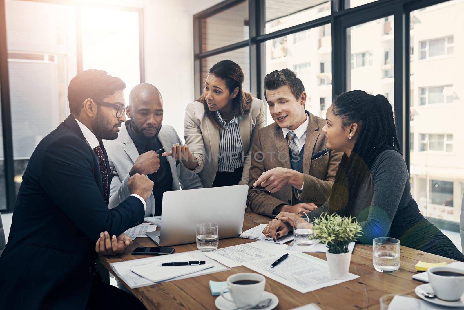 Open communication is vital for successful meetings. a group of young businesspeople using a laptop together during a meeting in a modern office. by YuriArcurs