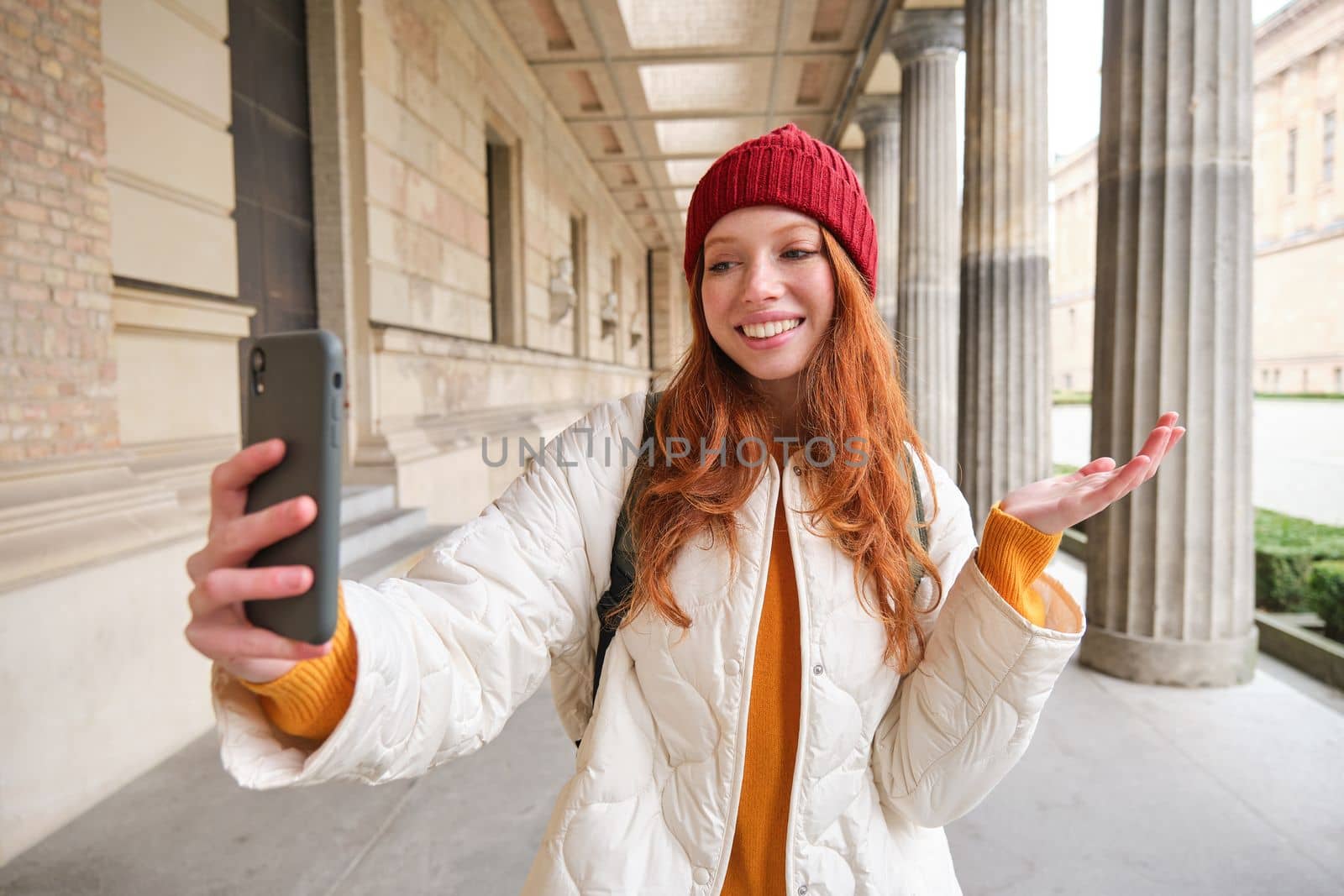 Happy girl tourist demonstrates something on video chat smartphone, shows sightseeing attraction to friend while on mobile phone app call.