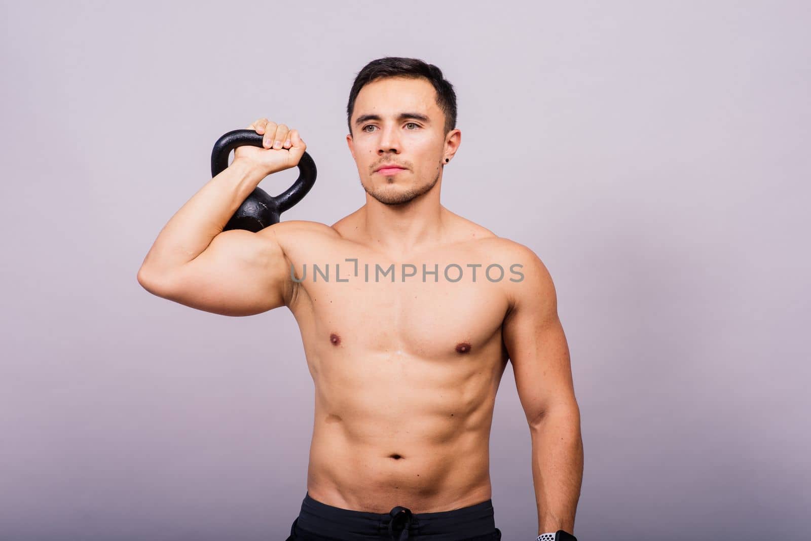 Handsome muscular man holding a kettle bell with copy space. Hispanic male athlete