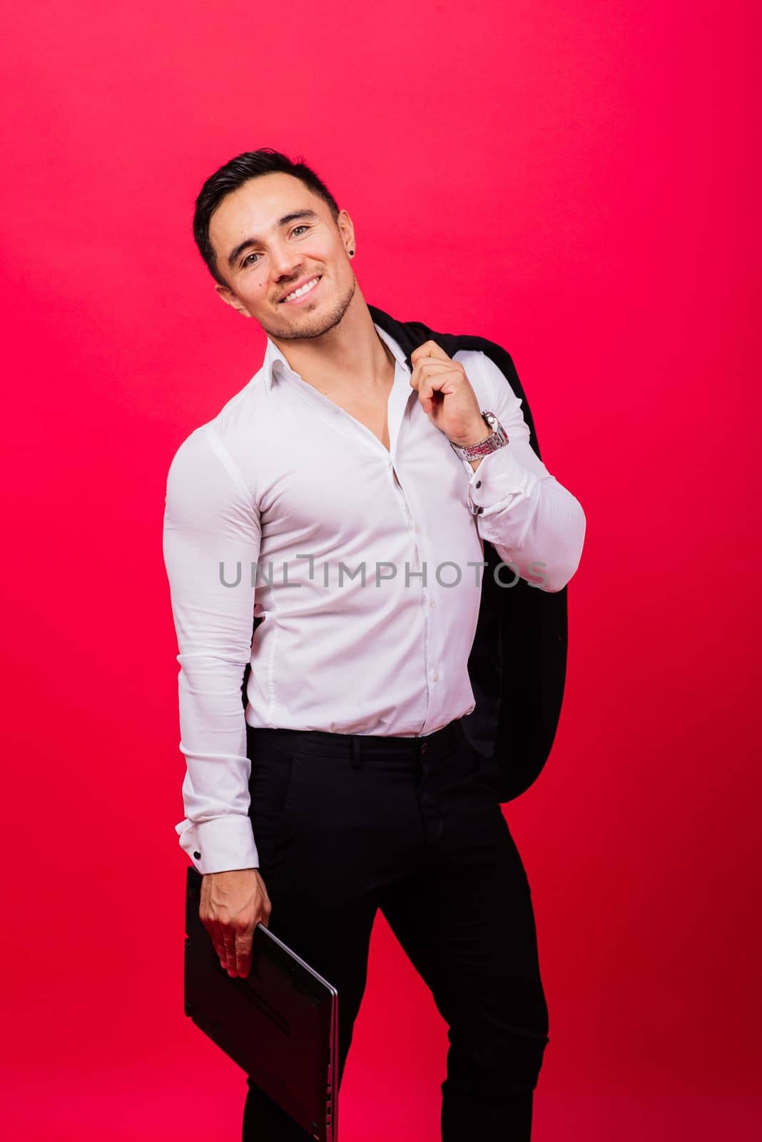 Image of young cheerful businessman in watch holding and using laptop isolated over red background by Zelenin