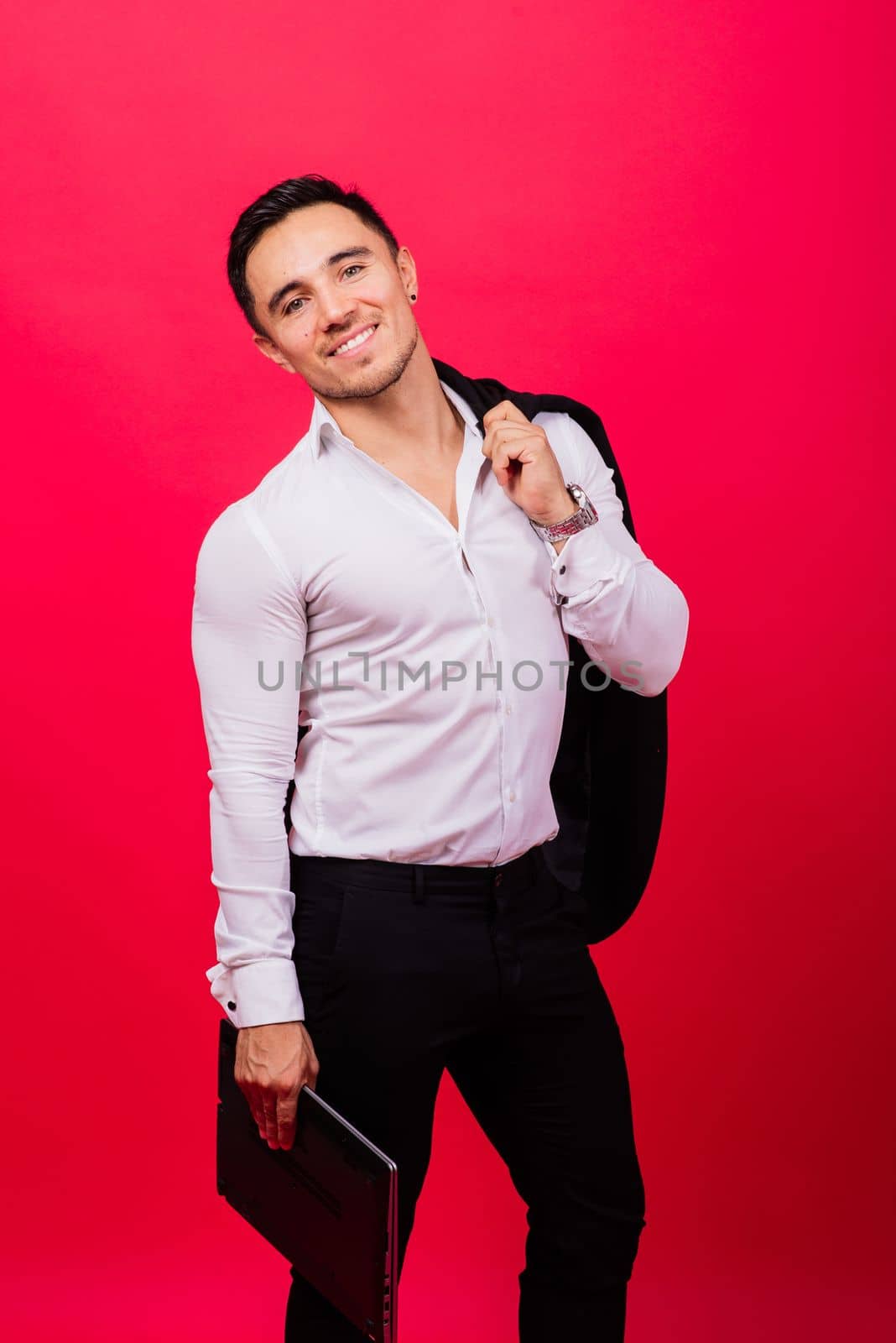 Image of young cheerful businessman holding and using laptop isolated over red background