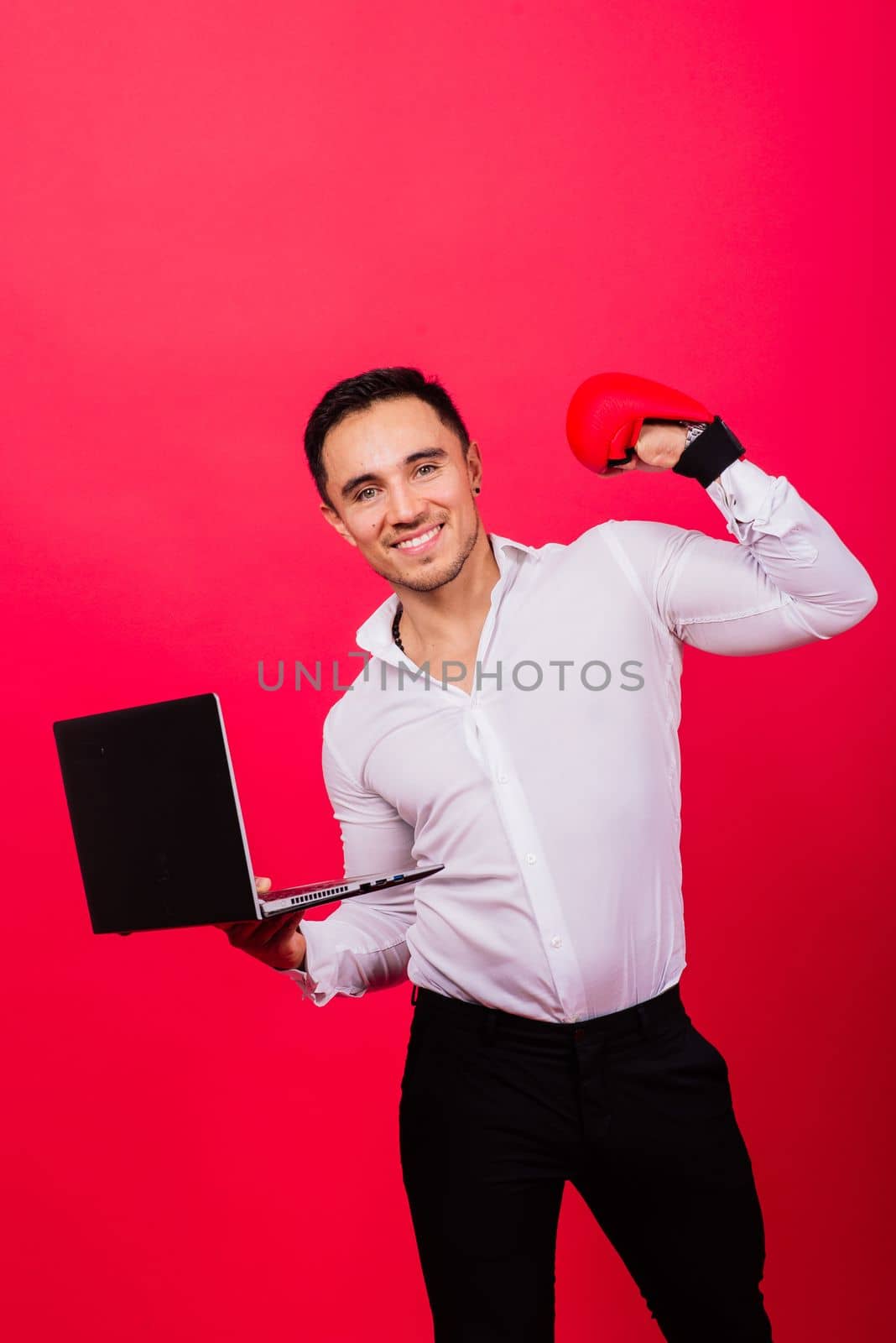 Image of young cheerful businessman holding and using laptop isolated over red background