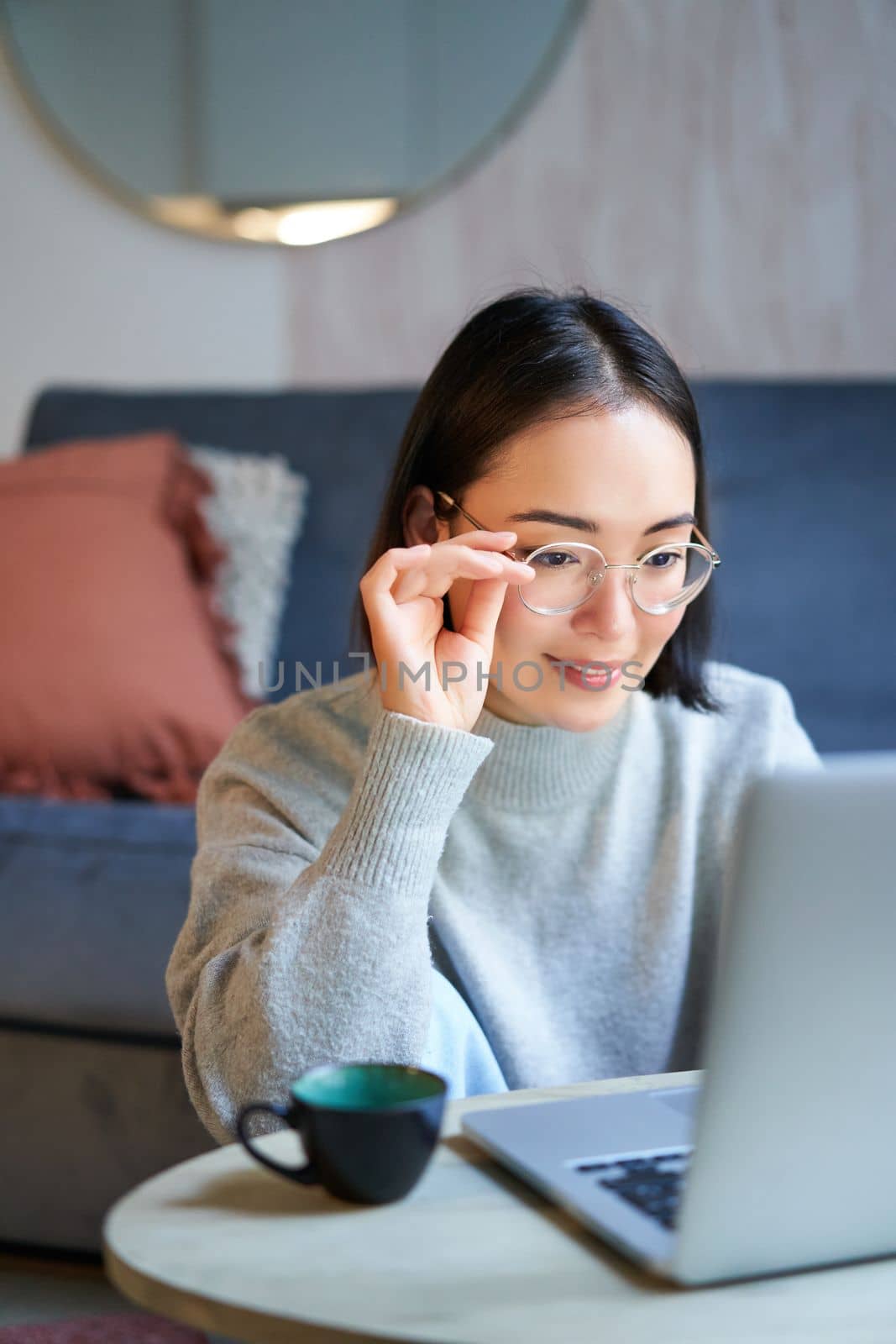 Young asian girl, freelancer professional sitting in living room and working with computer, studying at home using computer by Benzoix