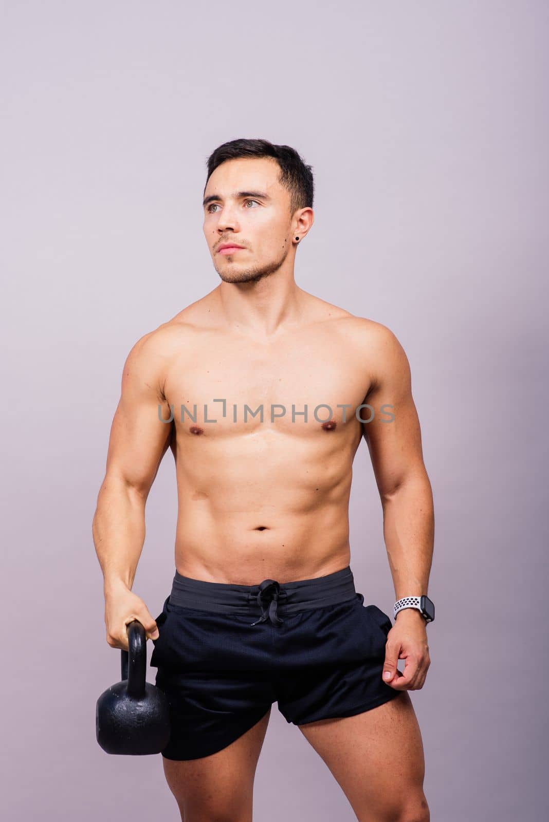 Handsome muscular man holding a kettle bell with copy space. Hispanic male athlete