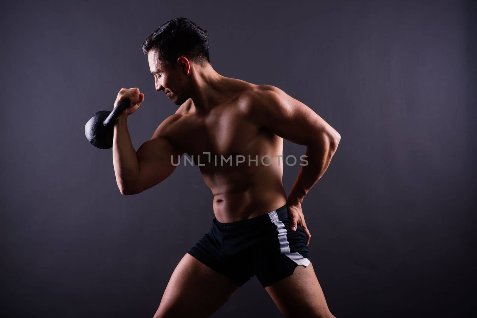 Sporty man working out with a kettlebell. Photo of man on dark background. Strength and motivation by Zelenin