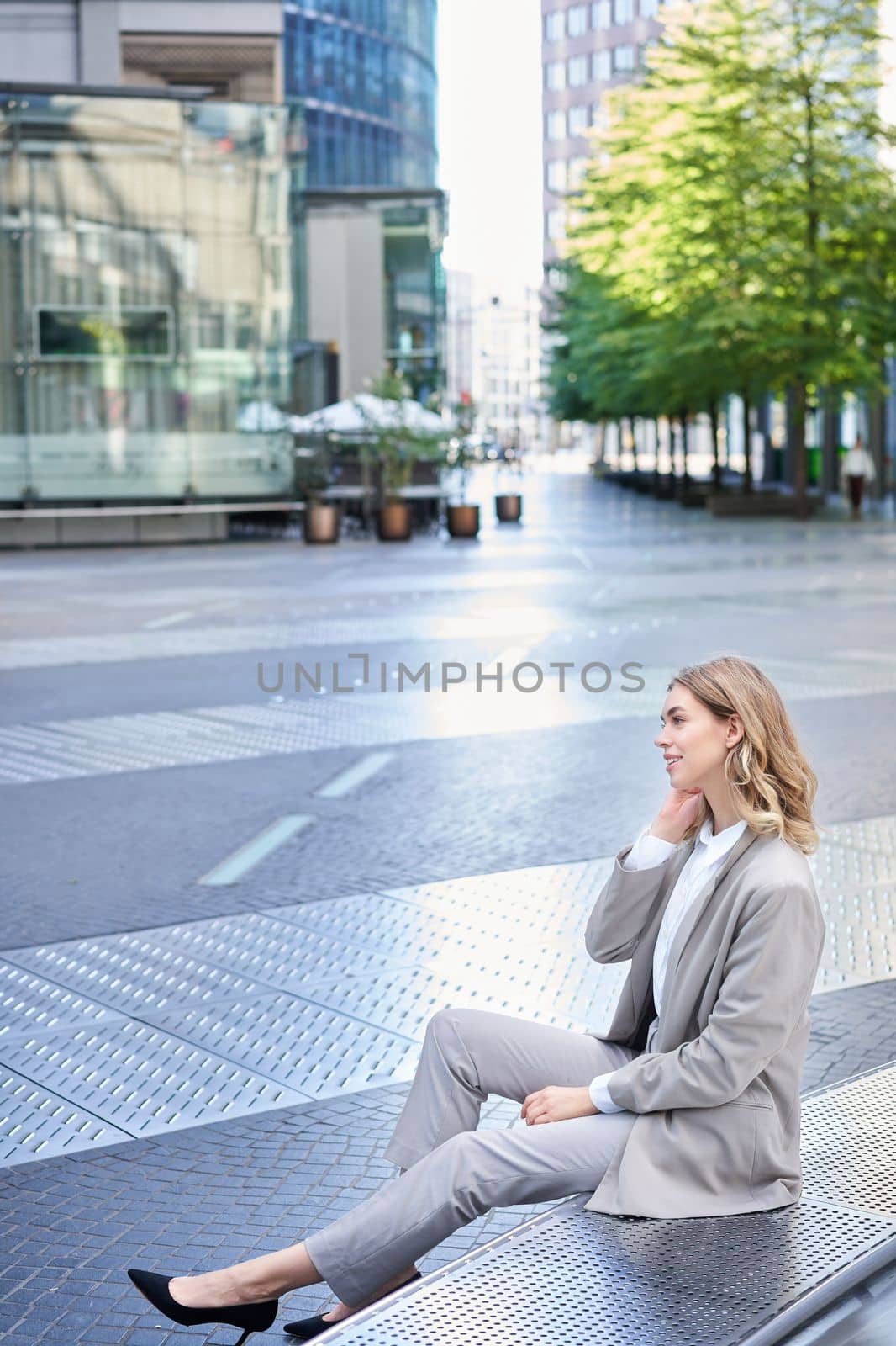 Vertical shot of smiling female entrepreneur in beige suit, corporate worker in office outfit. Girl dressed up for an interview by Benzoix