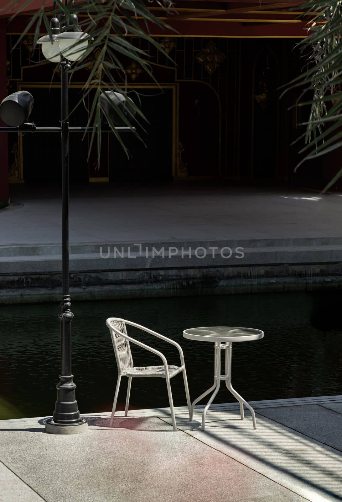 Bangkok, Thailand - 26 Jan, 2023 - The white metal chair and the table beside street lamp pole, Relaxing corner in the sunny day with good atmosphere, Space for text, Selective focus.