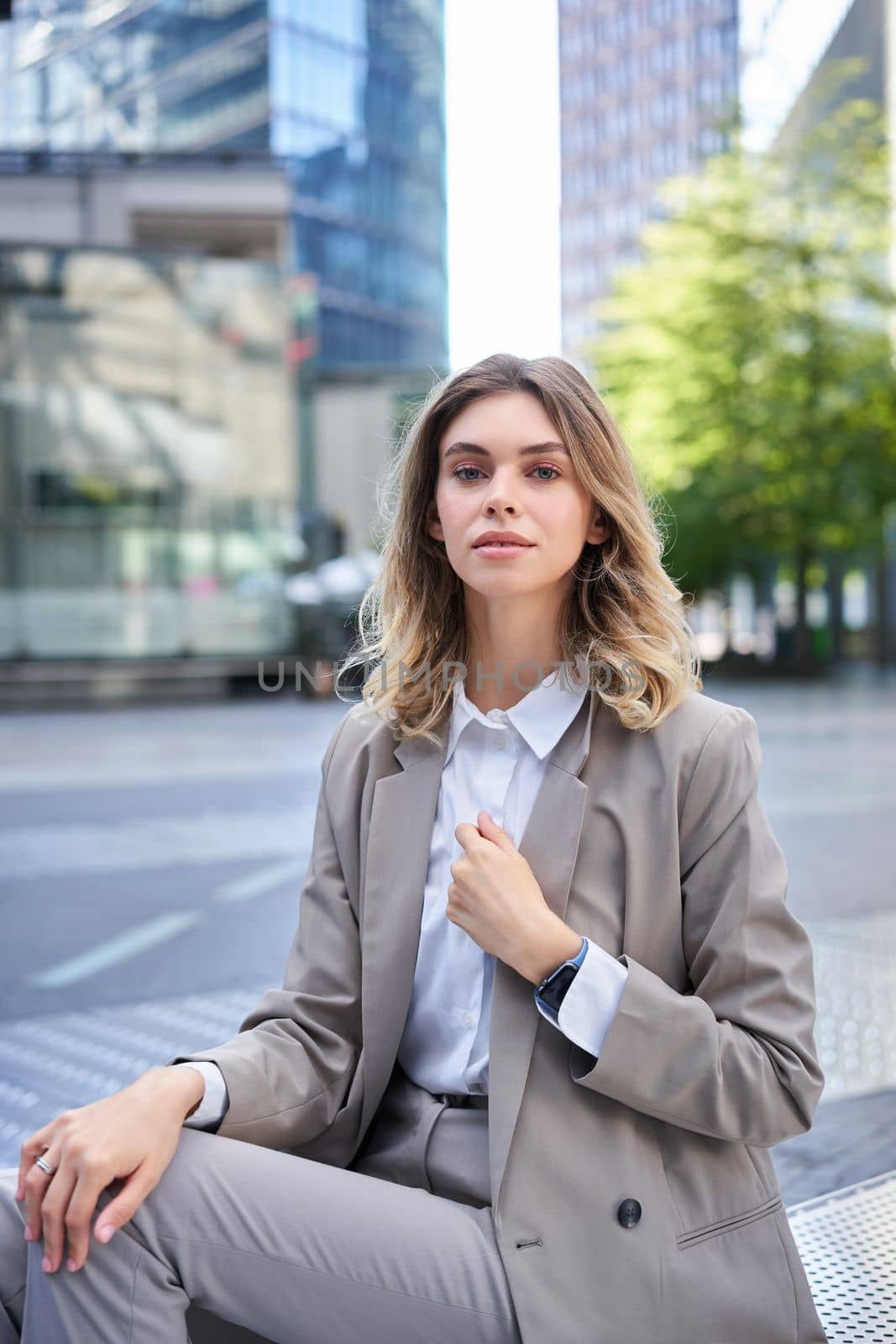 Vertical portrait of confident businesswoman in suit, adjust her blazer, looks self-assured. Candidate waits for an interview.