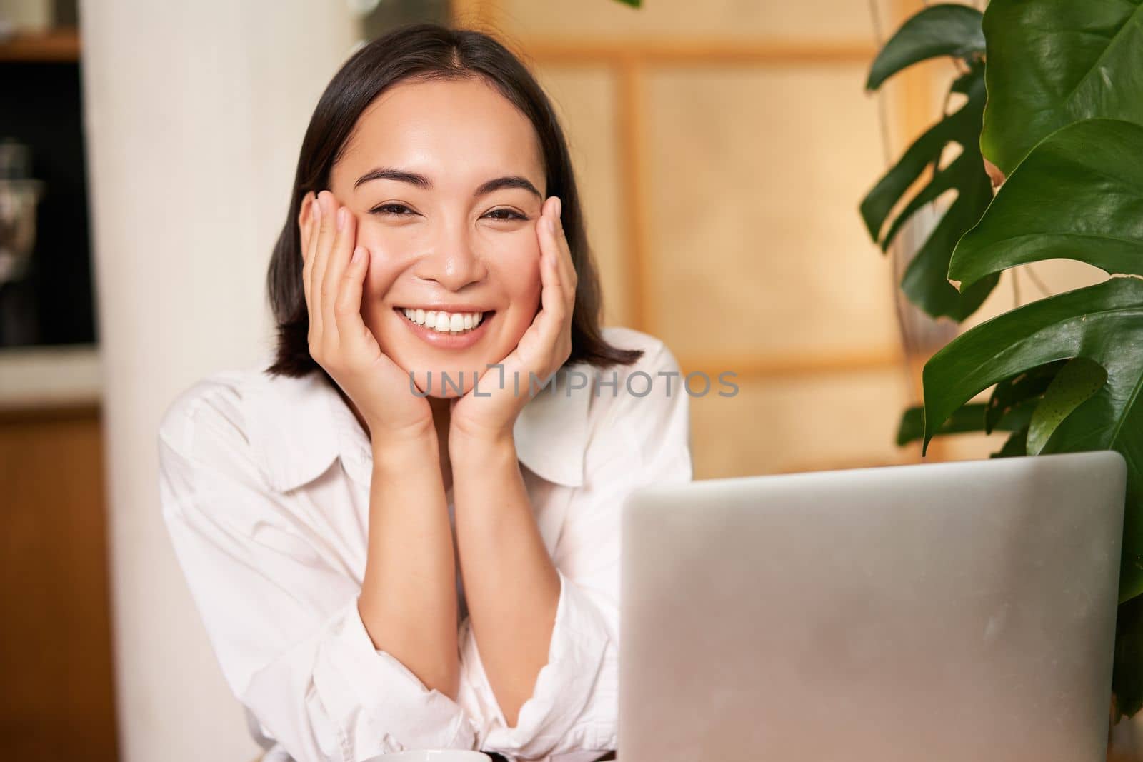 Beautiful young woman with happy smile, sitting in cafe with laptop, studying remotely, working online from distance. People and technology