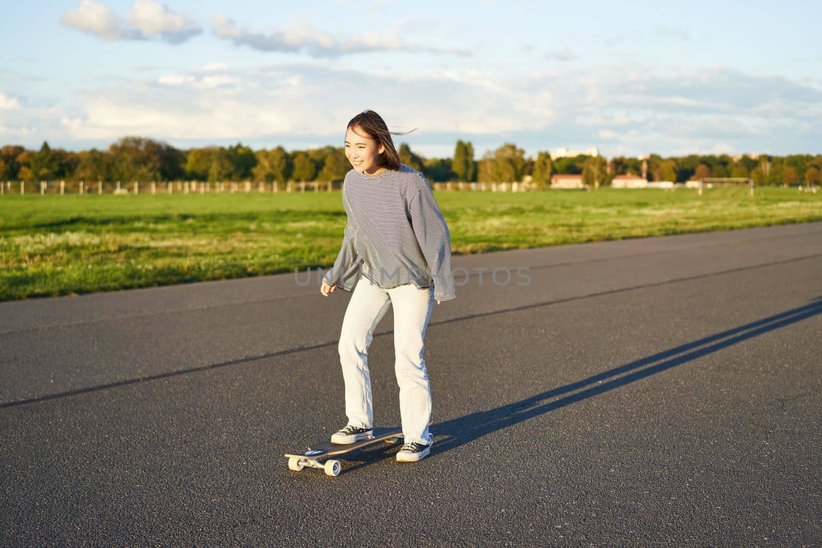 Hobbies and lifestyle. Young woman riding skateboard. Skater girl enjoying cruise on longboard on sunny day outdoors by Benzoix