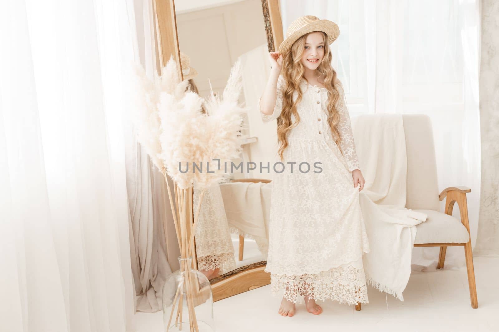 A beautiful teenage girl with long hair measures a straw hat in front of a mirror. Self-admiration of a blonde. selective focus