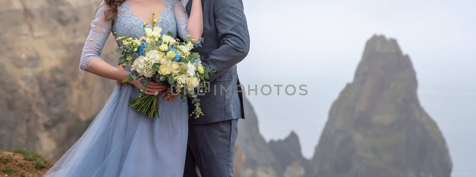 a couple standing in an embrace holding a beautiful bouquet of flowers, a girl dressed in a blue long dress, a man dressed in a suit. wedding concept by Matiunina