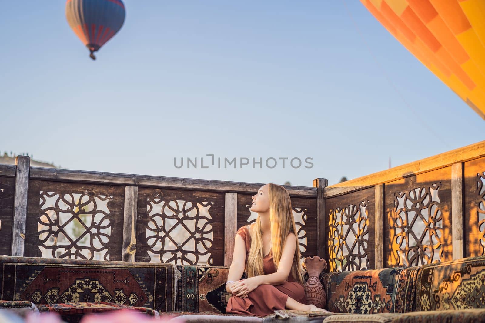 Tourist woman looking at hot air balloons in Cappadocia, Turkey. Happy Travel in Turkey concept. Woman on a mountain top enjoying wonderful view.